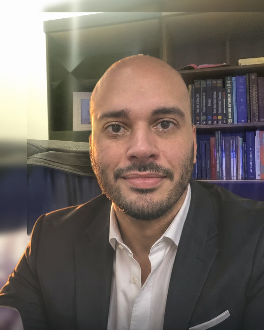 Nemuel Machado Alkmim de Oliveira, advogado, em frente à estante de livros do escritório